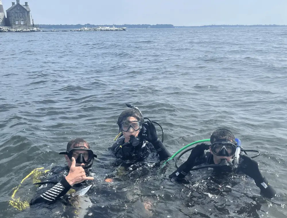 Divers in the water near the lighthouse — Wreck of the Maine